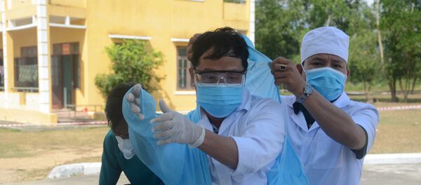 Cán bộ y tế mặc áo bảo hộ, khẩu trang trước khi vào chăm sóc sức khỏe cho các công dân được cách ly tại trung tâm. Cán bộ y tế mặc áo bảo hộ, khẩu trang trước khi vào chăm sóc sức khỏe cho các công dân được cách ly tại trung tâm. - Sputnik Việt Nam