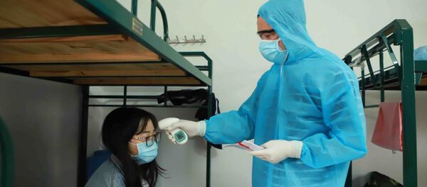 Bác sĩ Đỗ Xuân Bình, Trung tâm y tế thành phố Vĩnh Yên đo thân nhiệt cho một du học sinh đang cách ly tại Trung đoàn 834 Bộ Chỉ huy quân sự tỉnh Vĩnh Phúc.  - Sputnik Việt Nam