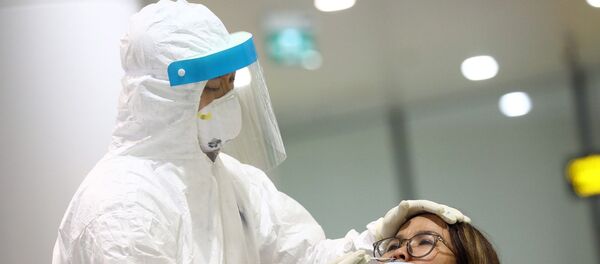 Nhân viên y tế lấy mẫu xét nghiệm của từng khách nhập cảnh ngay sau khi khách khai báo y tế và đo thân nhiệt. - Sputnik Việt Nam