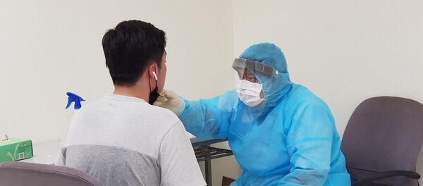 Nhân viên y tế của Trung tâm Kiểm dịch y tế quốc tế kiểm tra sức khỏe của hành khách nhập cảnh tại sân bay Tân Sơn Nhất Thành phố Hồ Chí Minh.  - Sputnik Việt Nam