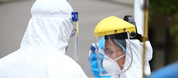 Nhân viên y tế được trang bị đầy đủ quần áo bảo hộ theo đúng quy định phục vụ trạm di động lấy mẫu xét nghiệm. - Sputnik Việt Nam