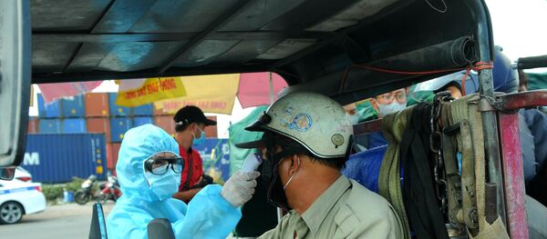 Lực lượng y tế kiểm tra thân nhiệt cho tài xế ra vào thành phố tại chân cầu Đồng Nai trên Xa lộ Hà Nội.  - Sputnik Việt Nam