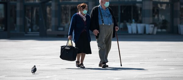 Một cặp vợ chồng người cao tuổi đeo khẩu trang trên đường phố Belgrade. - Sputnik Việt Nam