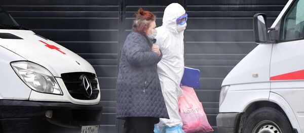 Một bác sĩ cứu thương giúp một bệnh nhân nhập viện đến trung tâm kiểm dịch coronavirus ở K Truyềnarka. Một bác sĩ cứu thương giúp một bệnh nhân nhập viện đến trung tâm kiểm dịch coronavirus ở K Truyềnarka. - Sputnik Việt Nam