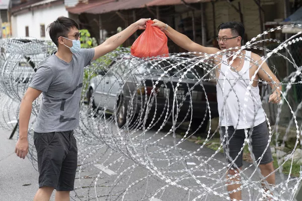 Người đàn ông chuyển cái túi qua hàng rào thép gai ở khu vực Kuala Lumpur, Malaysia Người đàn ông chuyển cái túi qua hàng rào thép gai ở khu vực Kuala Lumpur, Malaysia - Sputnik Việt Nam