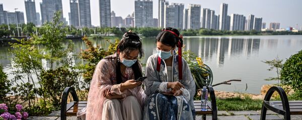 Phụ nữ trẻ đeo khẩu trang và bận trang phục truyền thống trên băng ghế ở công viên Vũ Hán, Trung Quốc - Sputnik Việt Nam