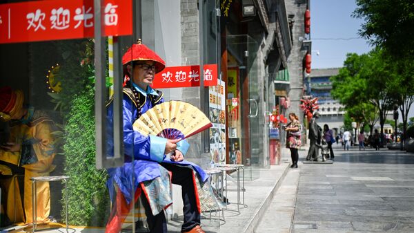 Người bán hàng bên lối vào một cửa hàng trên một con phố ở Bắc Kinh, Trung Quốc - Sputnik Việt Nam