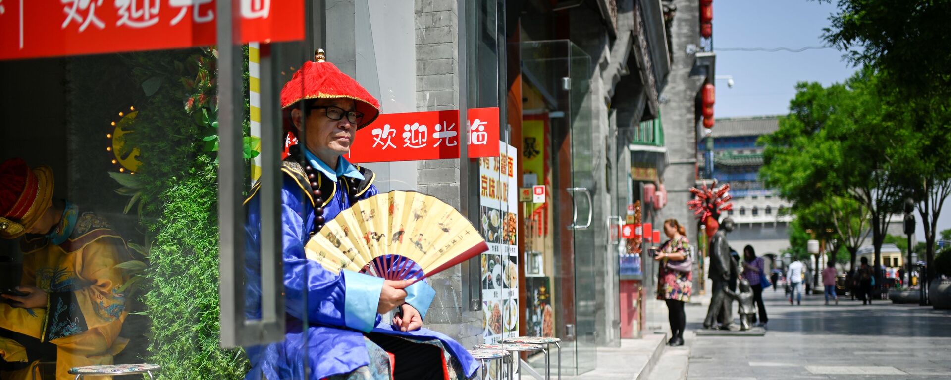 Người bán hàng bên lối vào một cửa hàng trên một con phố ở Bắc Kinh, Trung Quốc - Sputnik Việt Nam, 1920, 07.08.2025