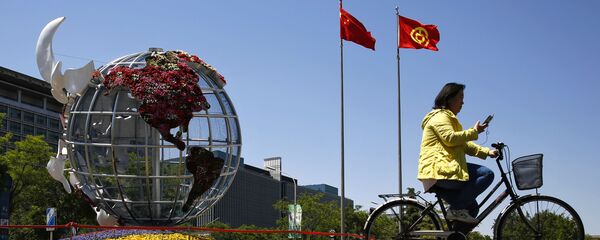 Một người phụ nữ đi xe đạp ở quảng trường trước một ngân hàng ở Bắc Kinh. Một người phụ nữ đi xe đạp ở quảng trường trước một ngân hàng ở Bắc Kinh. - Sputnik Việt Nam