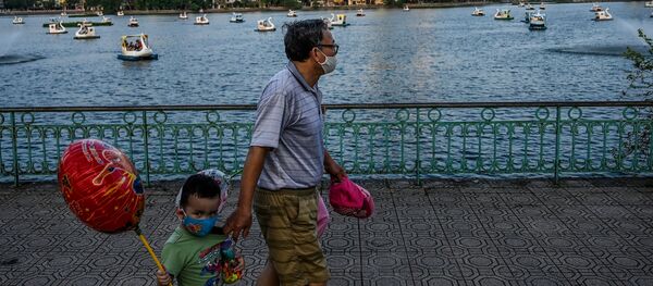 Một người đàn ông và một đứa trẻ đeo mặt nạ đi dạo bên hồ ở Hà Nội, Việt Nam - Sputnik Việt Nam