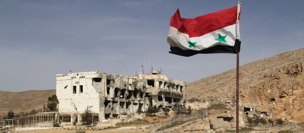Cờ Syria trước ngôi nhà bị tàn phá tại thị trấn Maaloula - Sputnik Việt Nam